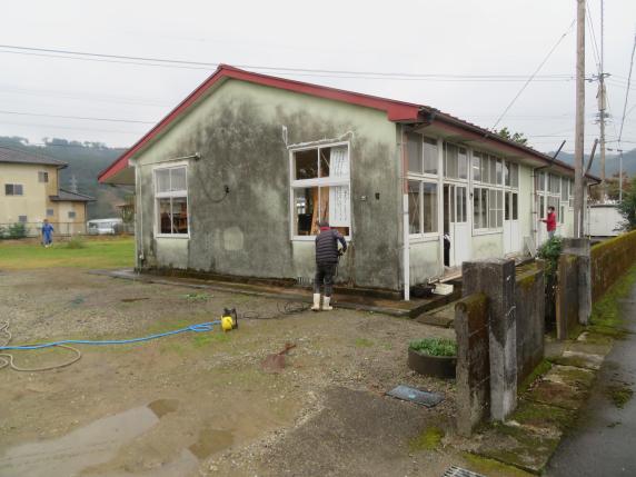 三人の男性が平屋の建物の清掃をしている写真