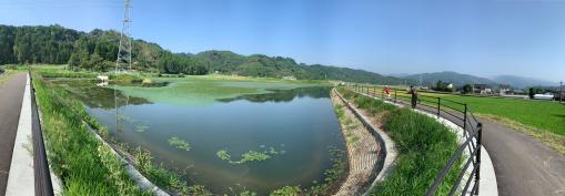 奥に山々が連なっており、その手前に大きな池が広がっている写真