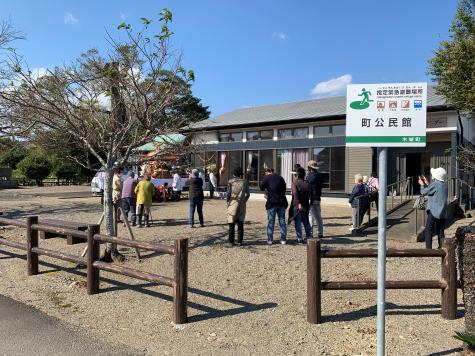 公民館の前で神輿を眺めている複数の男女の写真