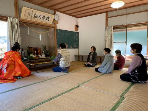 畳の上で宮司と複数の男女が神事を行っている写真