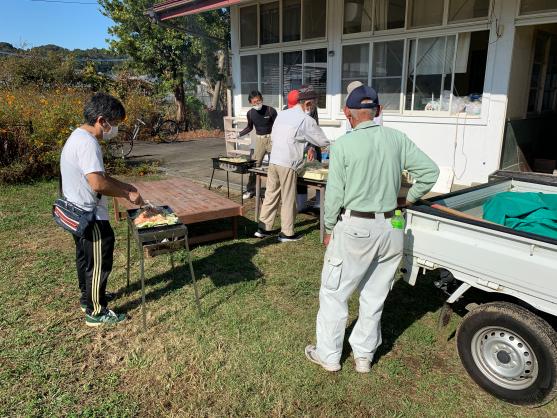 男性四人が建物の庭で焼きそばを作っている写真