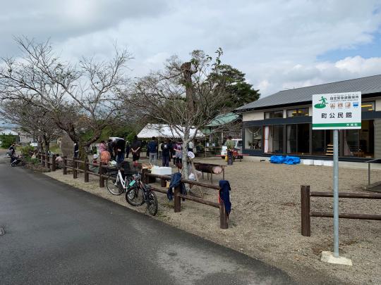 建物と木の間に人だかりがあり自転車が何台か止まってる様子の写真