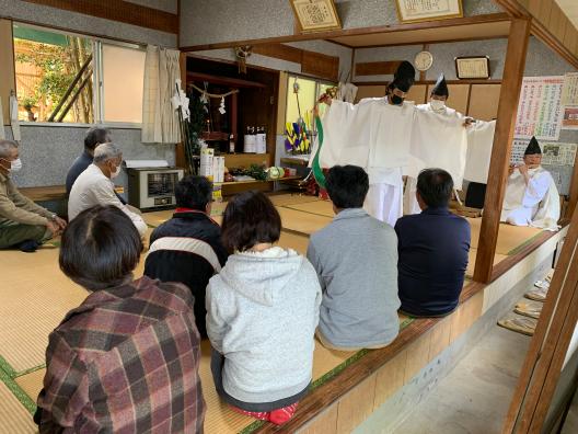 複数の男女の前で神主が踊りを踊っている様子の写真