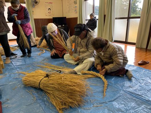 男性と女性が縄を編んでいる写真