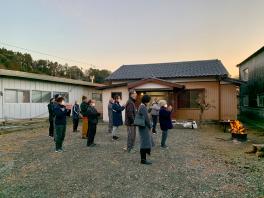 日の出の時刻に合わせ平屋の前で右を向いて手を合わせ祈っている人たちの写真