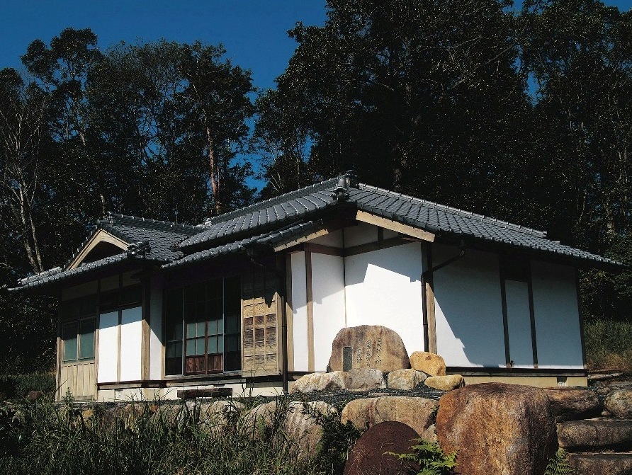 森林の中に建つ瓦屋根の平屋の武者小路実篤記念館の写真