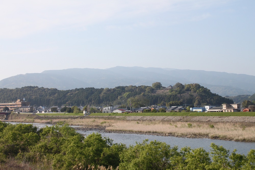 山々の前に木々や民家や川が連なって見える風景の写真