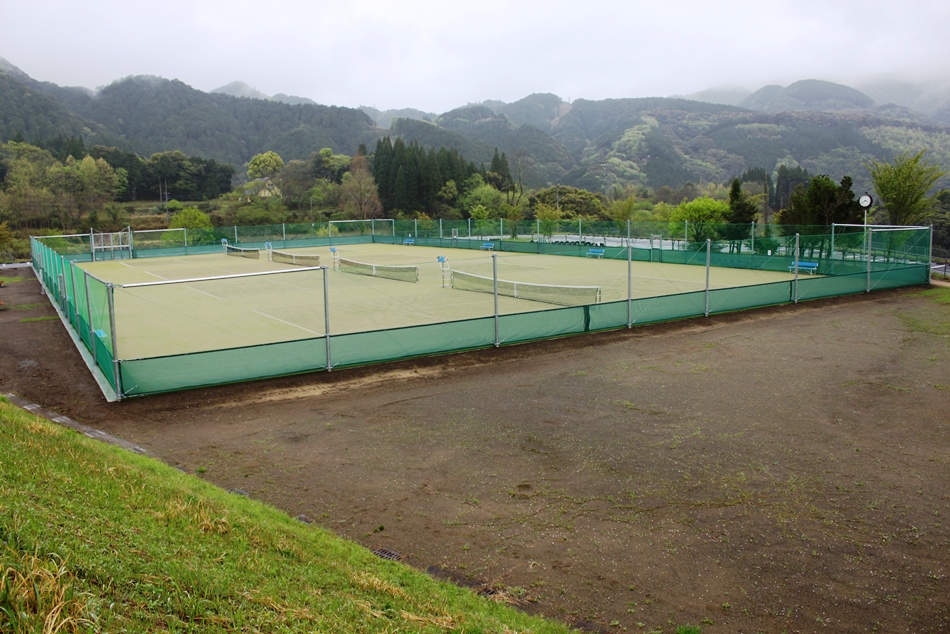 4面ある芝生のテニスコートの遠景の写真